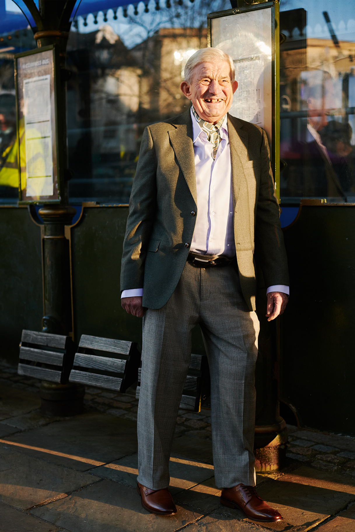 Documentary photograph capturing a lone man waiting patiently at a bus stop